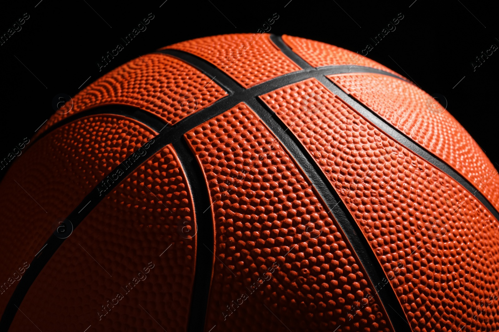 Photo of Orange basketball ball on black background, closeup