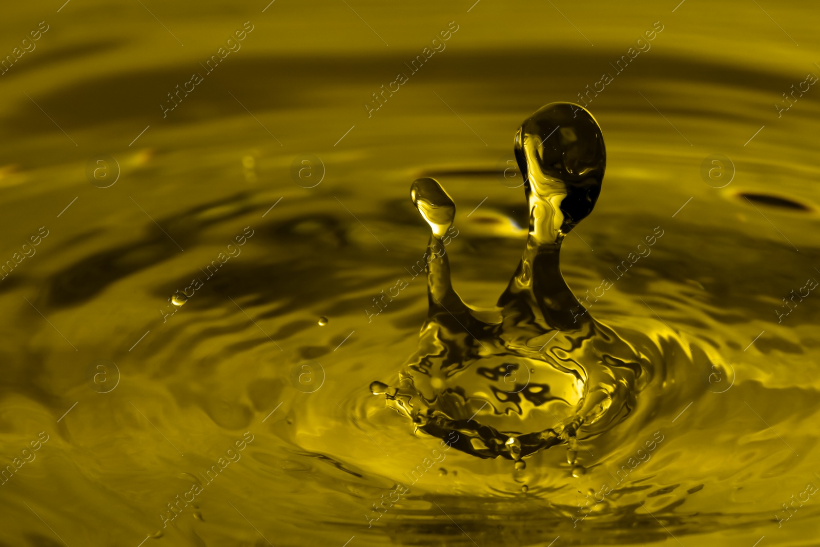 Image of Splash of golden oily liquid with drops as background, closeup. Space for text