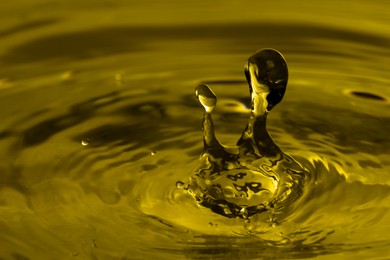 Image of Splash of golden oily liquid with drops as background, closeup. Space for text