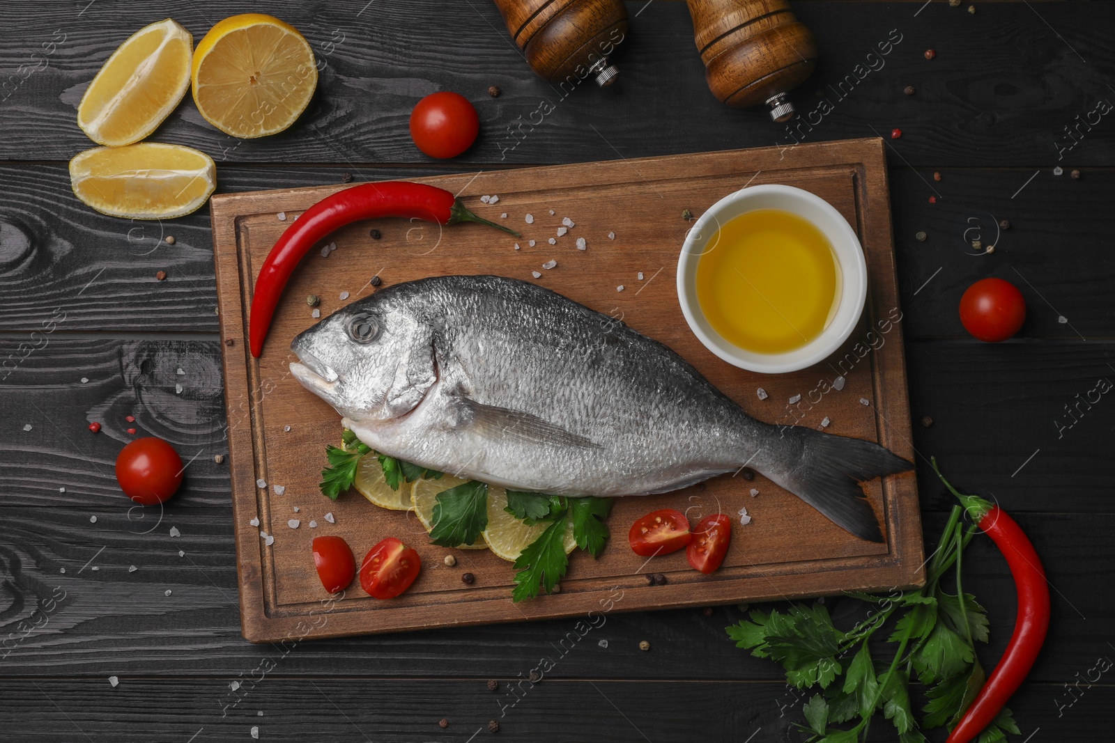 Photo of Flat lay composition with fresh raw dorado fish and spices on black wooden table