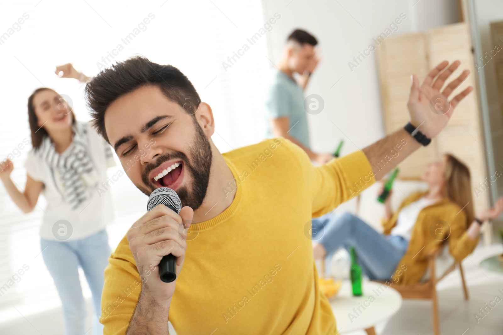 Photo of Young man singing karaoke with friends at home