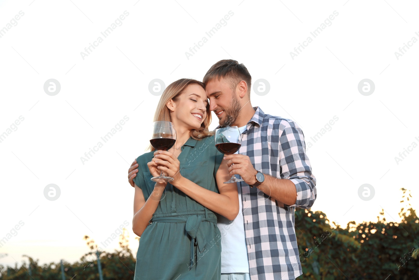 Photo of Young romantic couple holding glasses of wine at vineyard