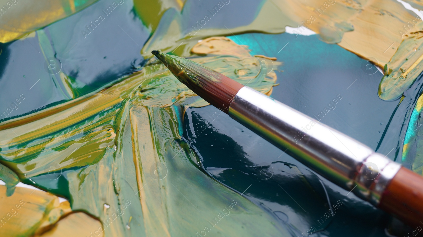 Photo of Brush on artist's palette with mixed paints, closeup