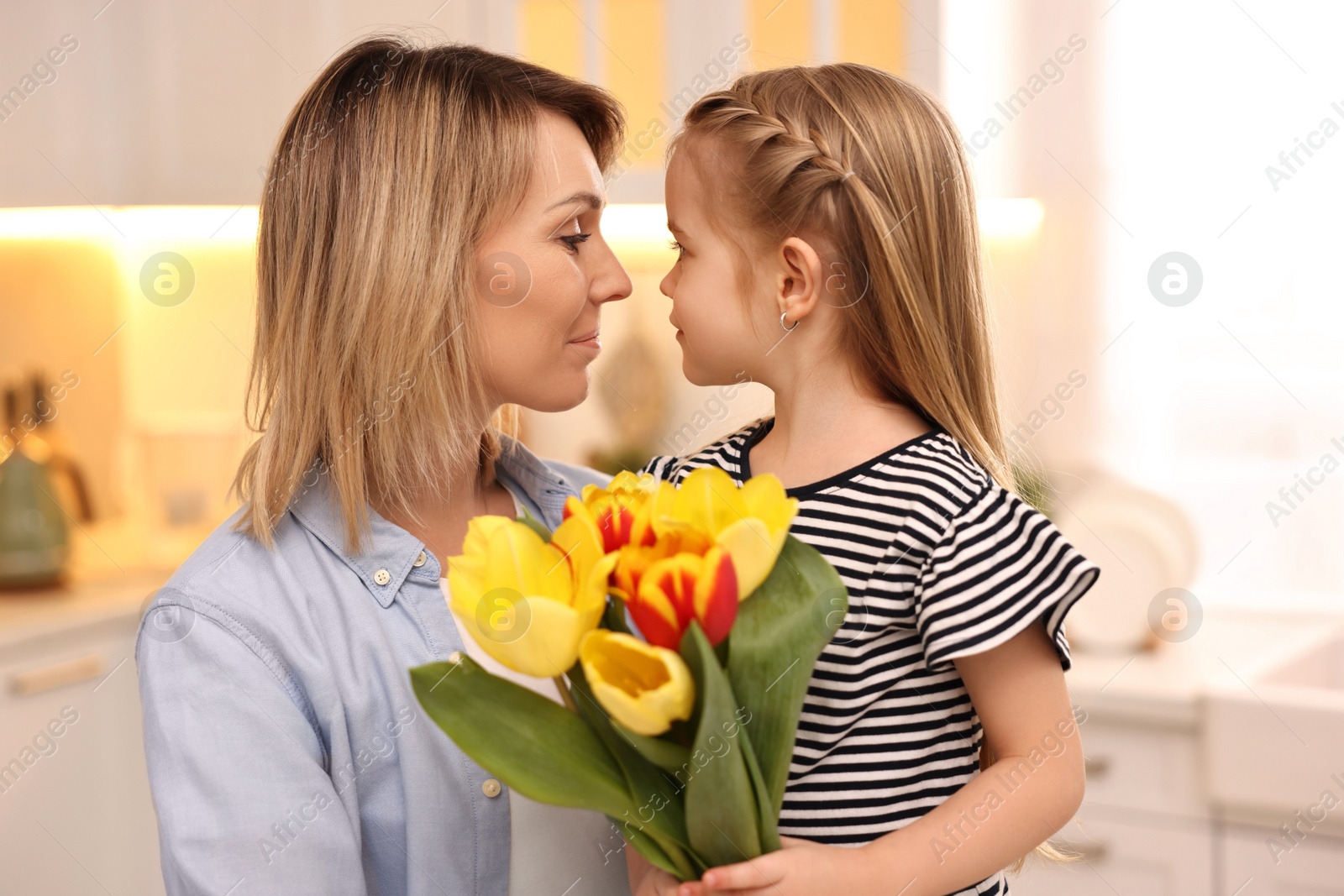 Photo of Little daughter congratulating her mom with bouquet of beautiful tulips at home. Happy Mother's Day