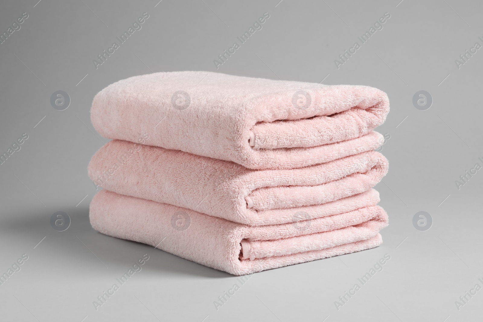 Photo of Stack of fresh towels on light background