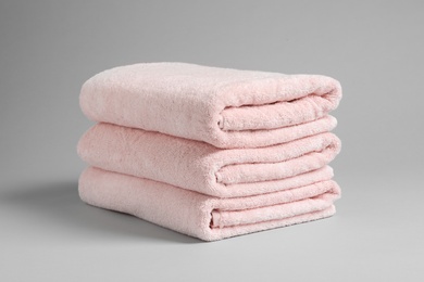 Stack of fresh towels on light background