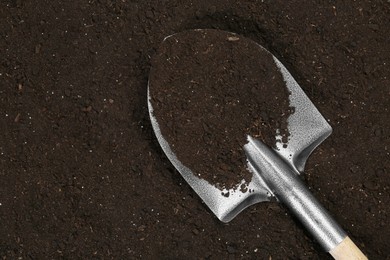 Photo of Metal shovel on fertile soil, top view and space for text. Gardening tool