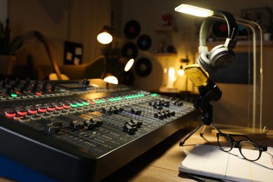 Photo of Microphone and professional mixing console on table in radio studio