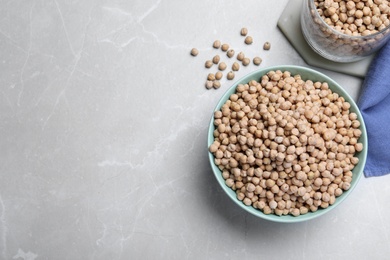 Photo of Chickpeas in bowl on light grey table, flat lay. Space for text