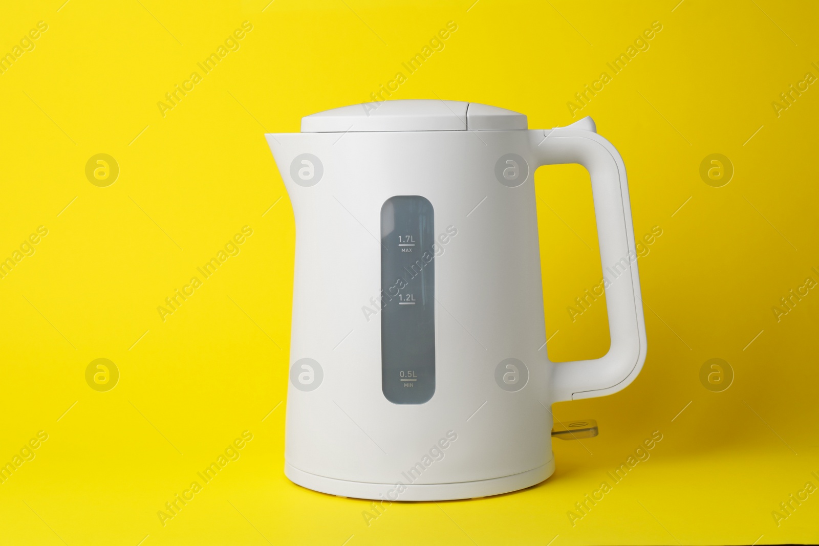 Photo of Modern plastic electric kettle on yellow background