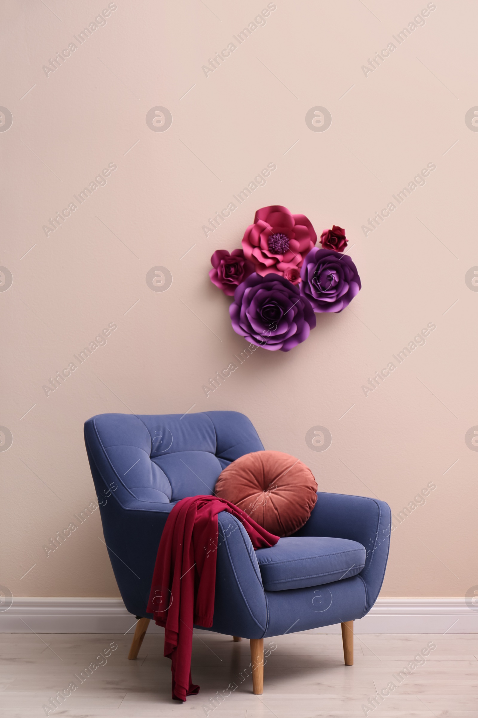 Photo of Comfortable armchair near wall with floral decor in room. Interior design
