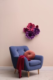 Photo of Comfortable armchair near wall with floral decor in room. Interior design