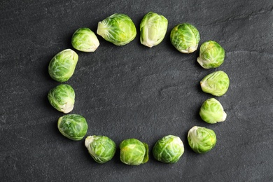 Photo of Frame made with Brussels sprouts on black slate table, flat lay. Space for text