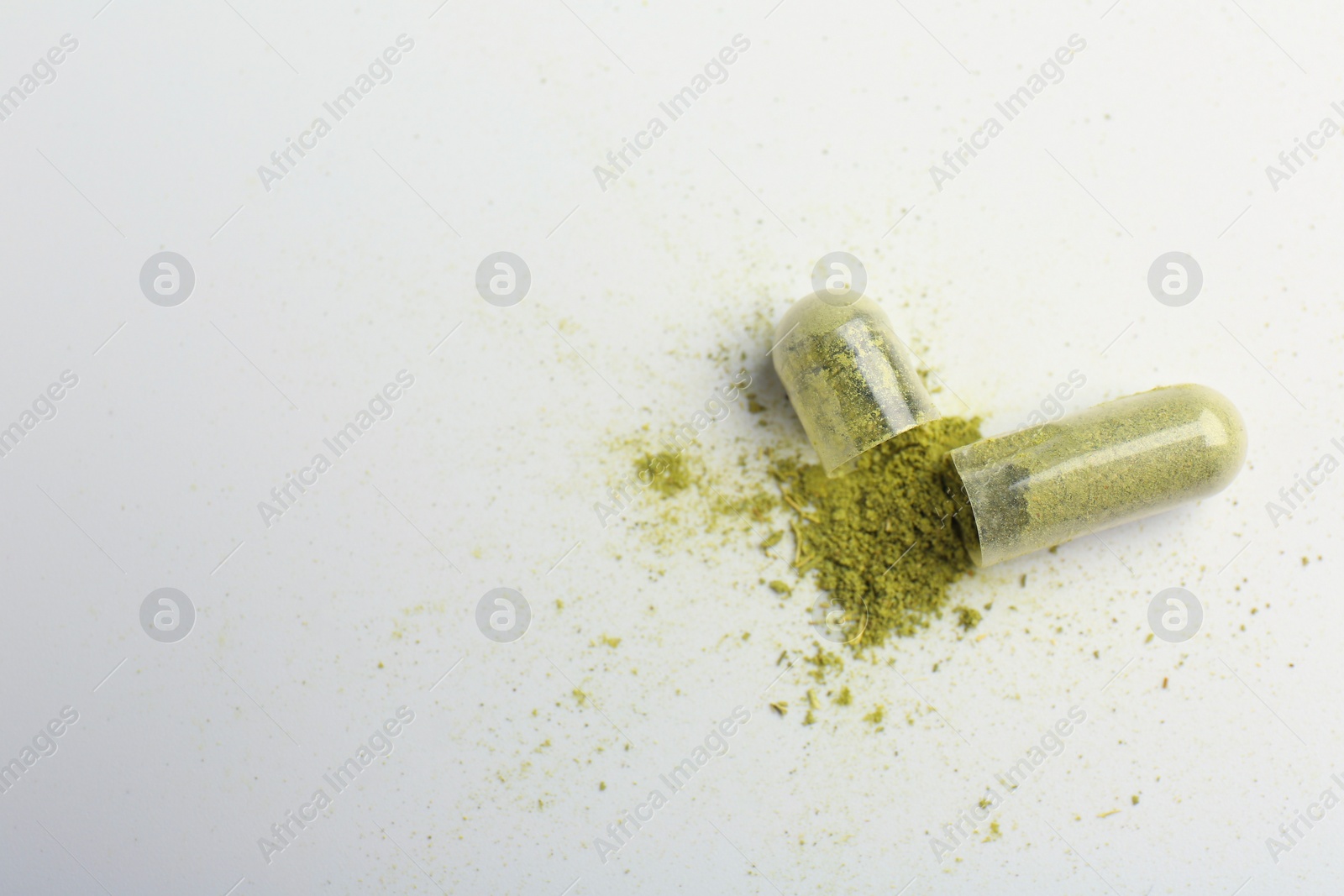 Photo of Broken light green vitamin capsule on white background, top view. Space for text