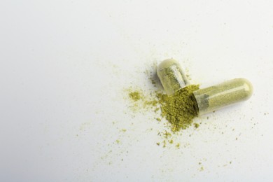 Broken light green vitamin capsule on white background, top view. Space for text