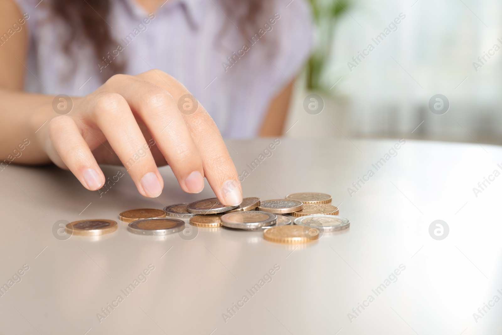 Photo of Young woman counting coins at table, closeup. Space for text