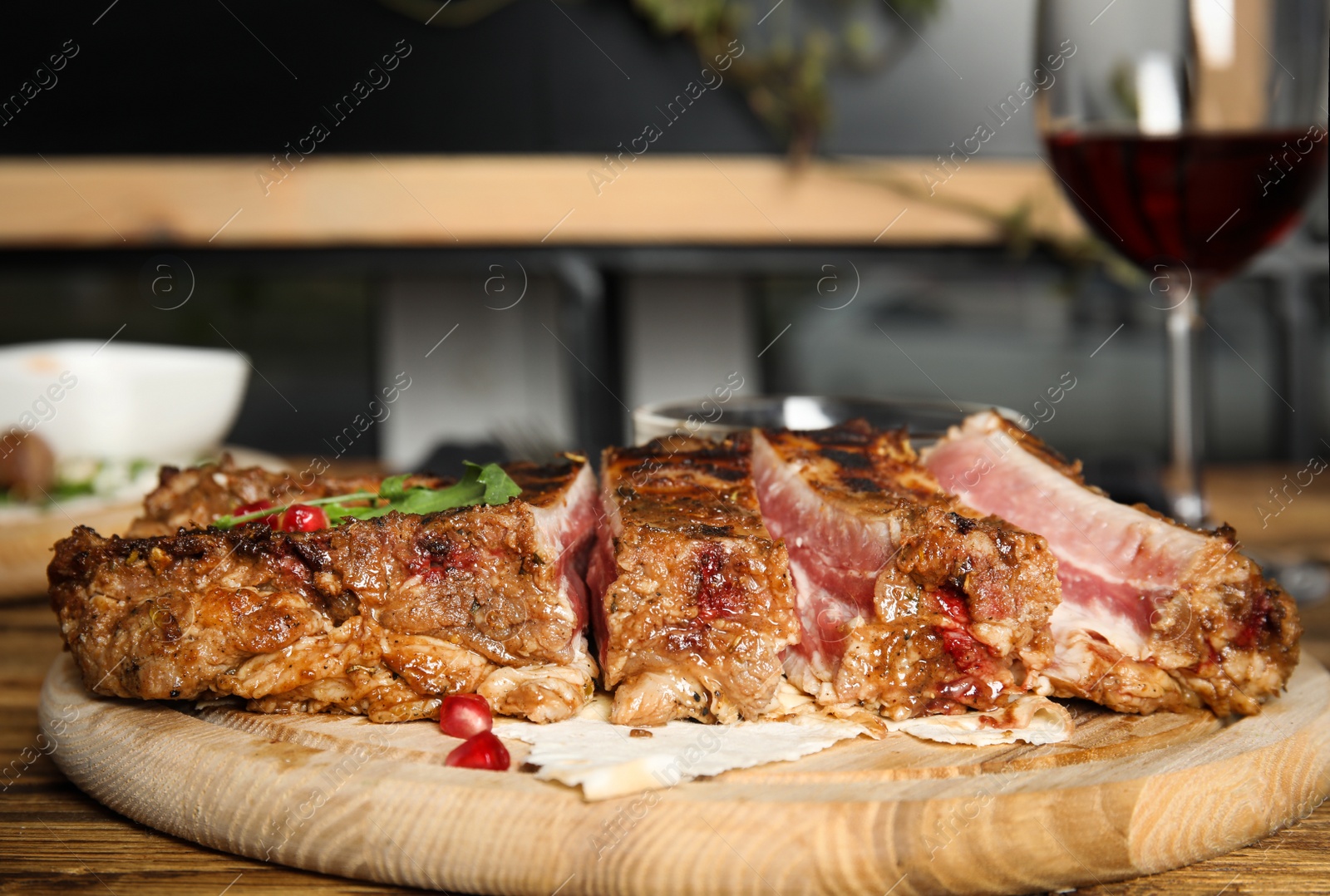 Photo of Delicious grilled ribs served on wooden table indoors, closeup