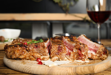 Photo of Delicious grilled ribs served on wooden table indoors, closeup