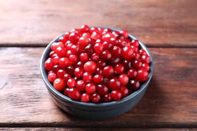 Photo of Fresh ripe cranberries in bowl on wooden table