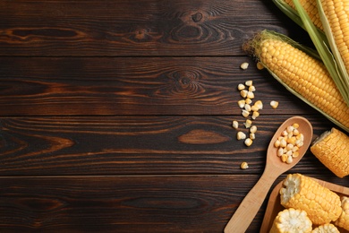 Tasty sweet corn cobs on wooden table, flat lay. Space for text
