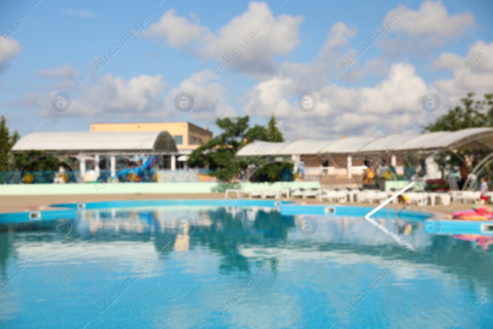 Photo of Blurred view of outdoor swimming pool with clear water on sunny day. Summer vacation