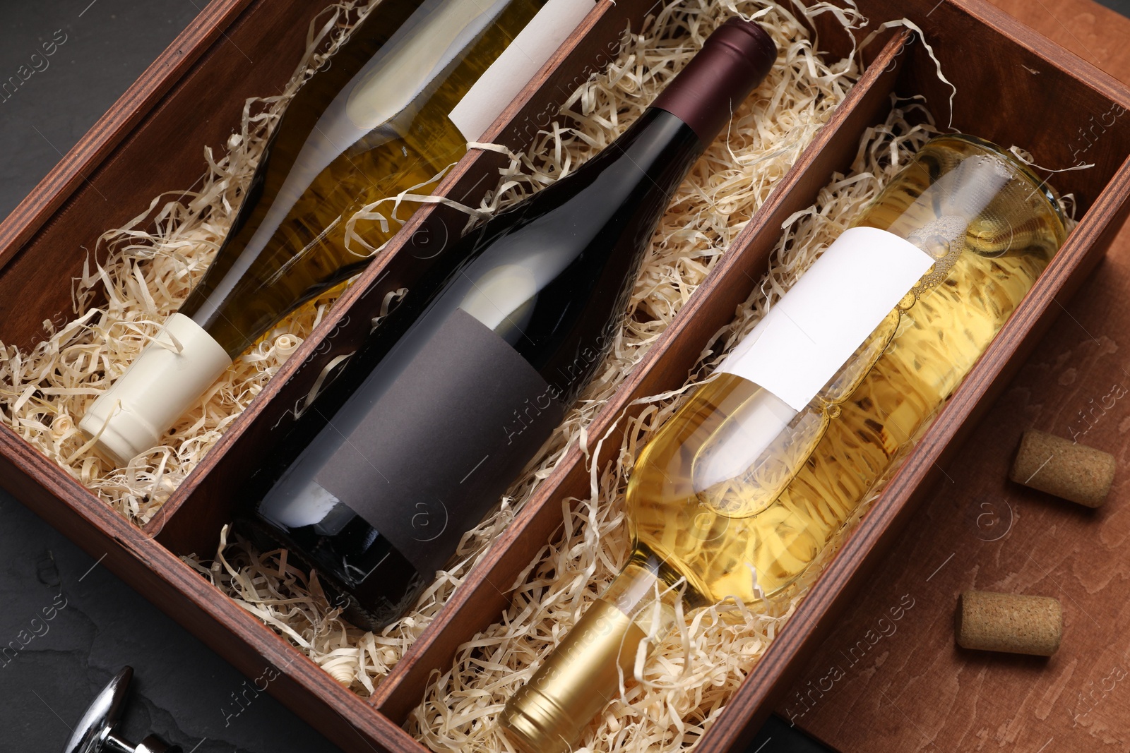 Photo of Box with wine bottles on dark table, top view