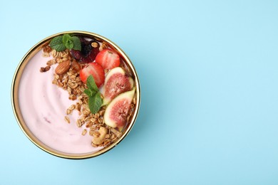 Photo of Bowl with yogurt, fruits and granola on light blue background, top view. Space for text