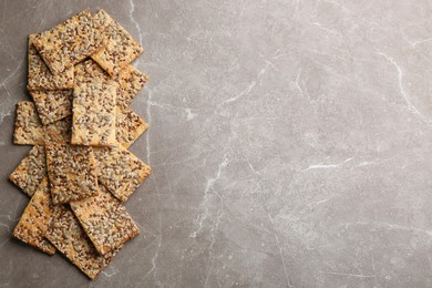 Photo of Many delicious crackers on grey table, flat lay. Space for text
