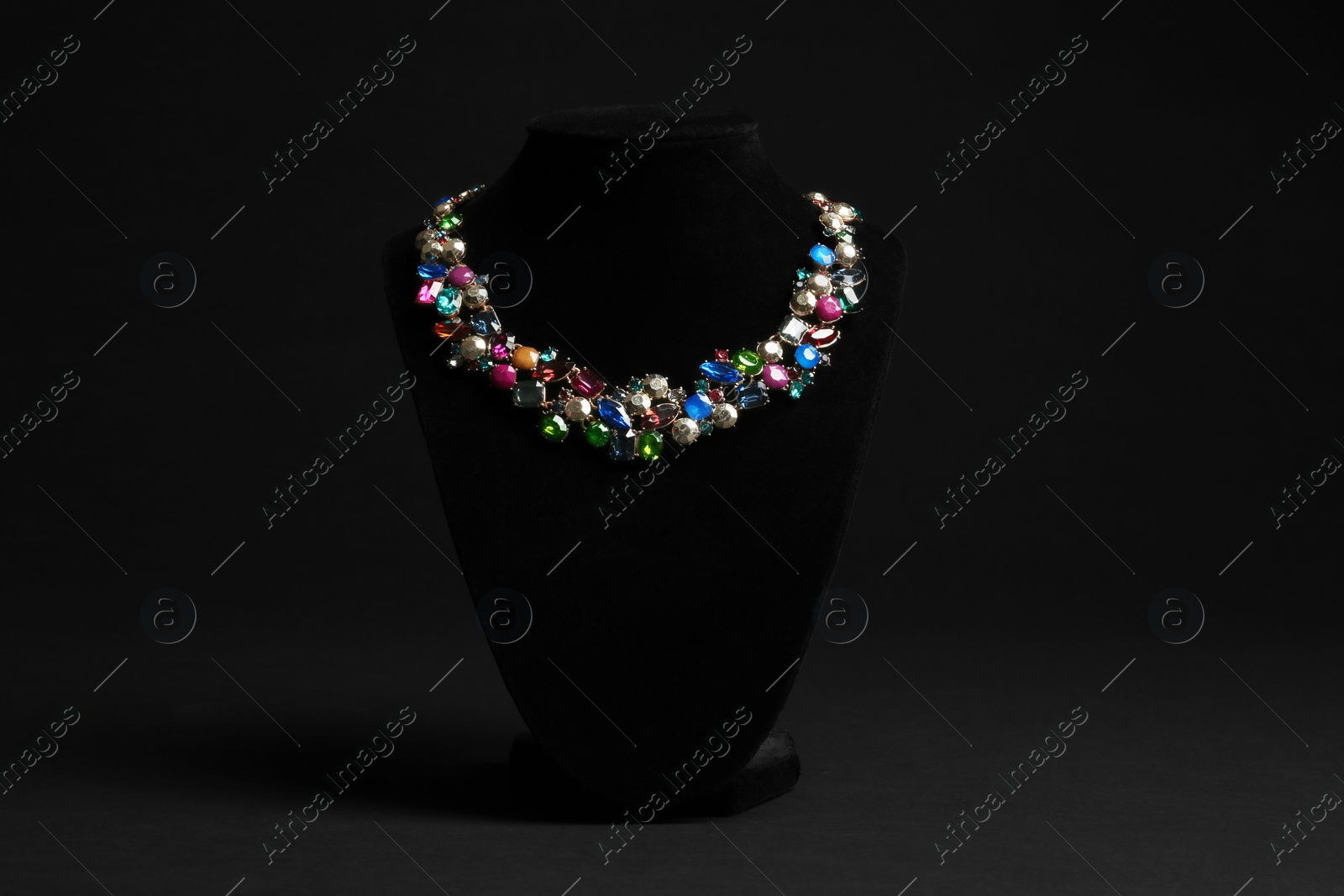 Photo of Elegant necklace on stand against black background. Luxury jewelry