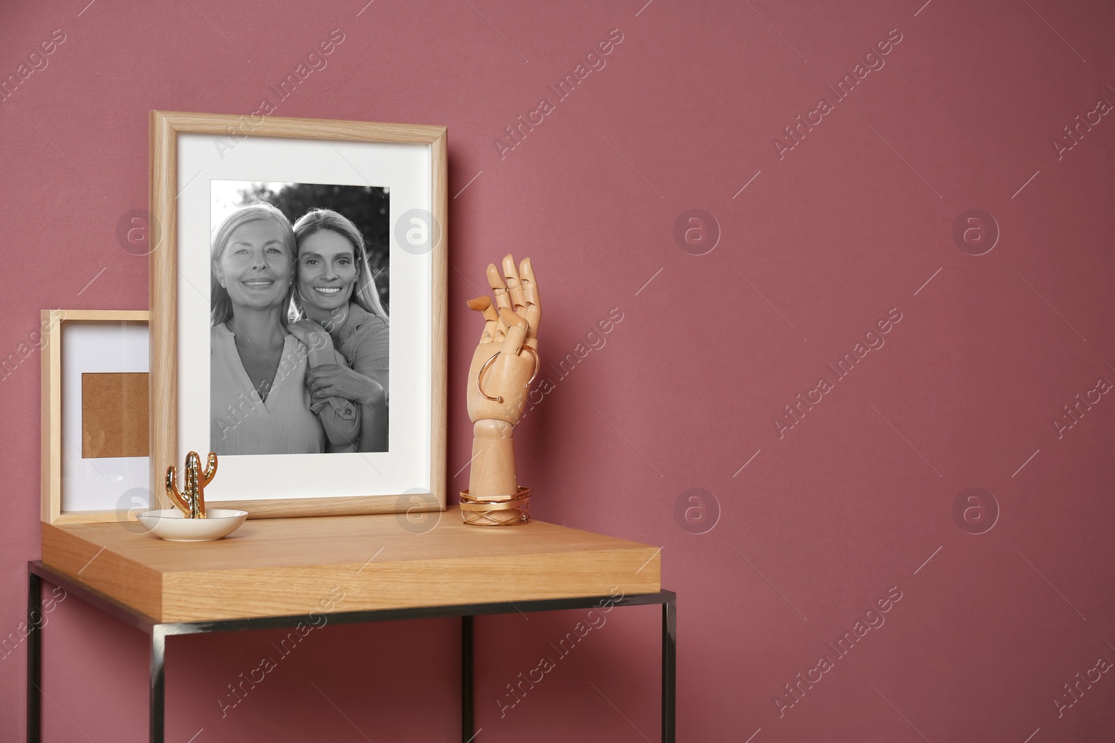 Image of Black and white family portrait of mother and daughter in photo frame on table near color wall