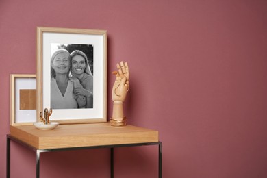 Black and white family portrait of mother and daughter in photo frame on table near color wall