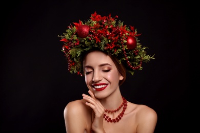 Photo of Beautiful young woman wearing Christmas wreath on black background