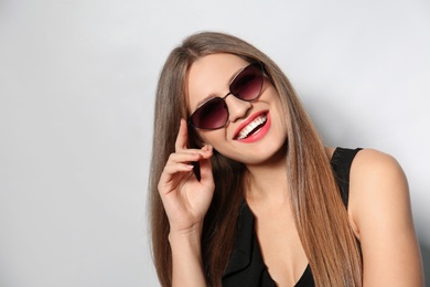 Photo of Young woman wearing stylish sunglasses on light background