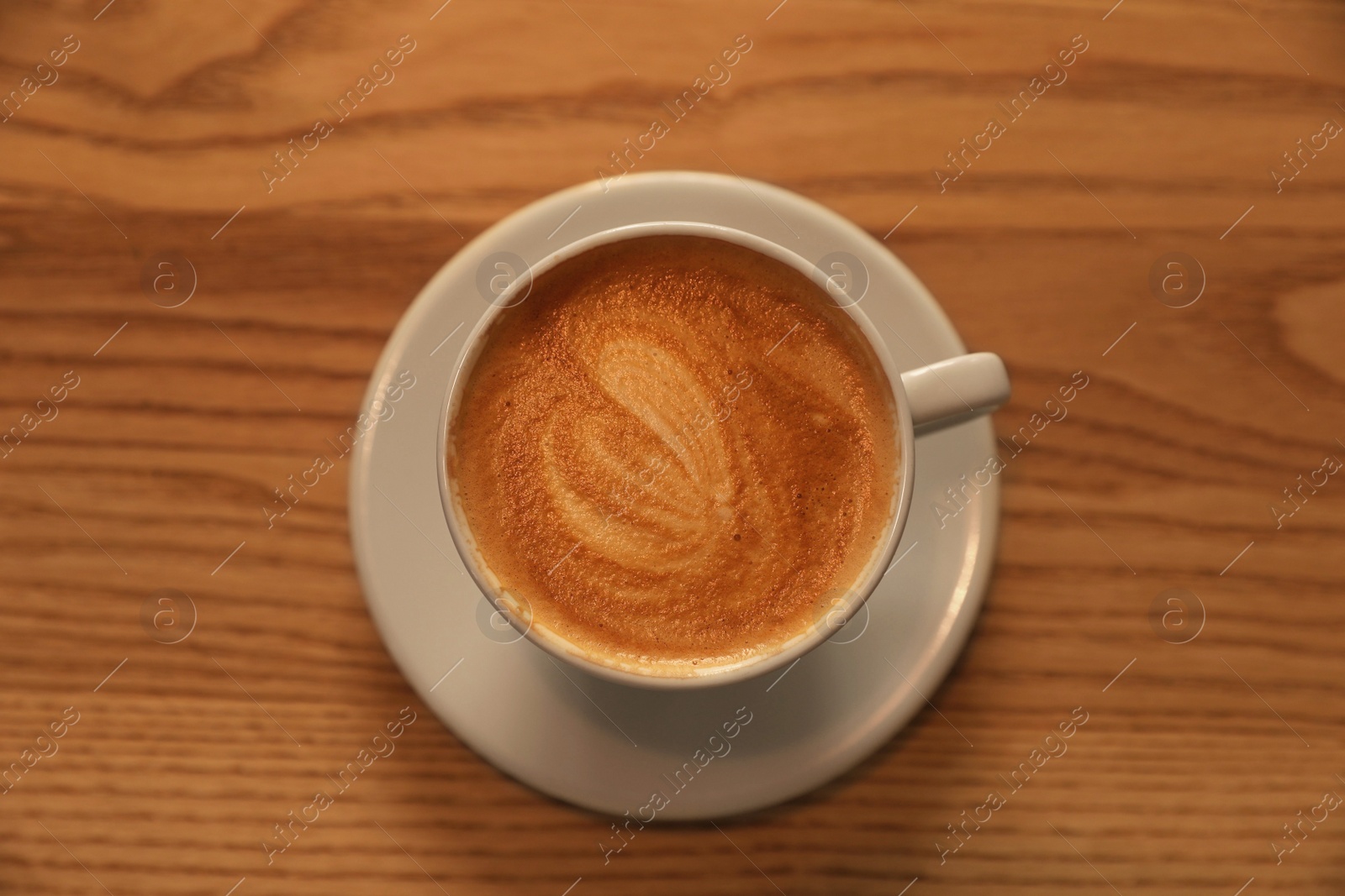 Photo of Cup of aromatic hot coffee on wooden table, top view