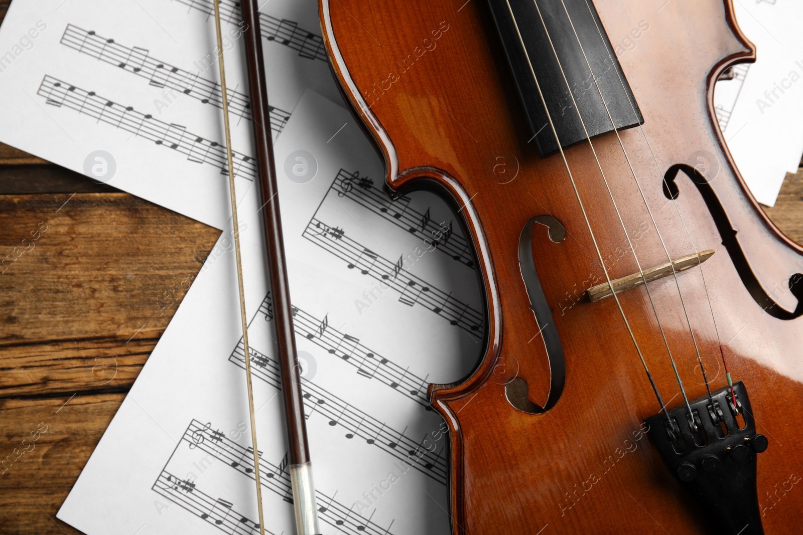 Photo of Beautiful violin, bow and note sheets on wooden table, flat lay