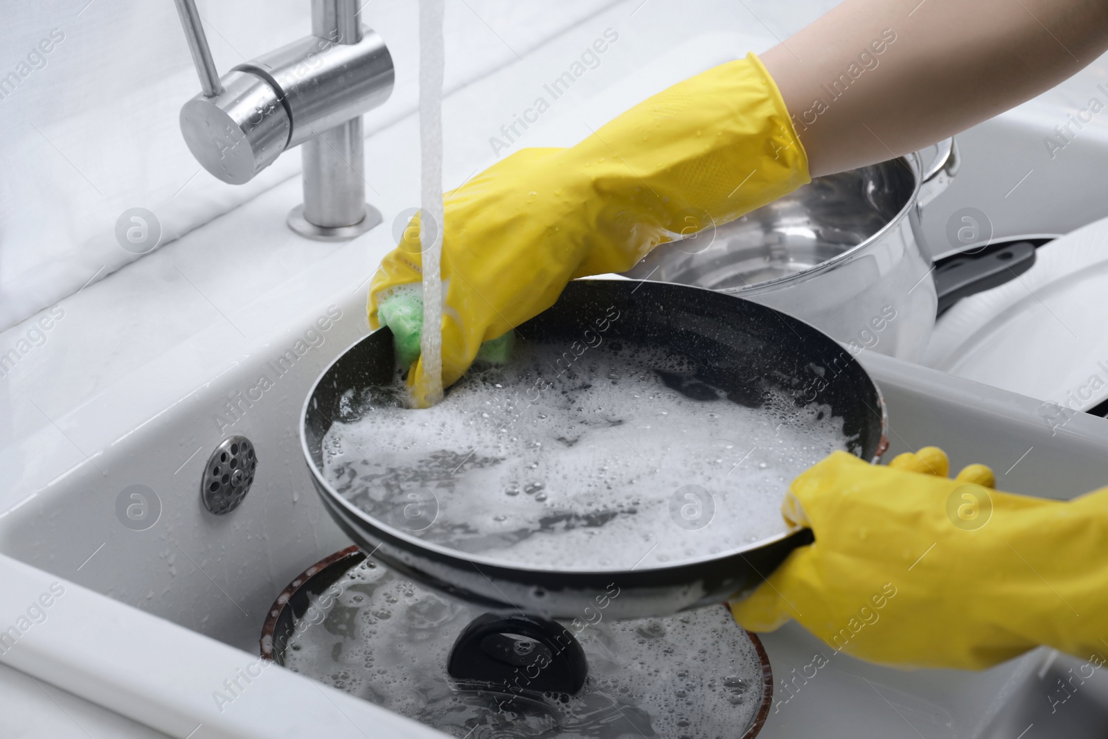 Photo of Woman washing dirty dishes in kitchen sink, closeup