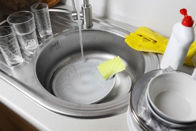 Washing plates and sponge in kitchen sink