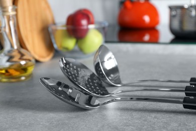 Photo of Set of different cooking utensils on grey countertop in kitchen, closeup