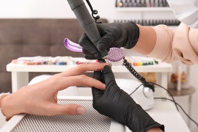 Professional manicurist working with client in salon, closeup