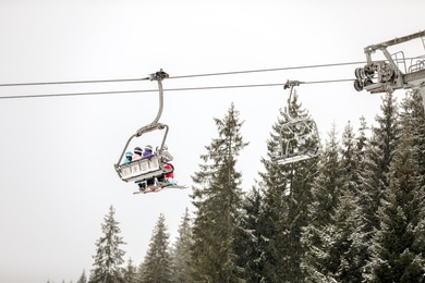 Photo of People using ski lift at mountain resort. Winter vacation