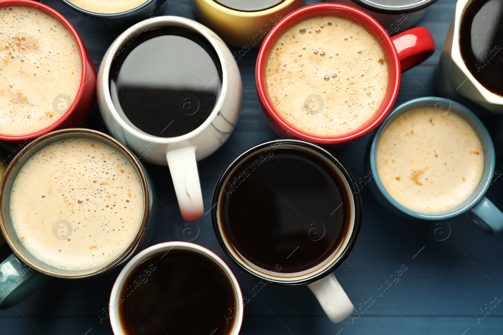 Photo of Many cups of different coffee drinks on blue wooden table, flat lay