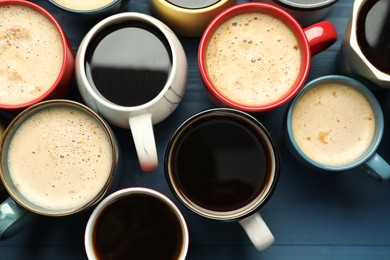 Many cups of different coffee drinks on blue wooden table, flat lay