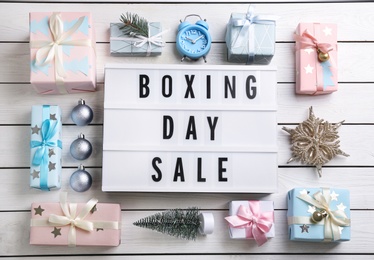 Photo of Flat lay composition with Boxing Day Sale sign and Christmas gifts on white wooden table