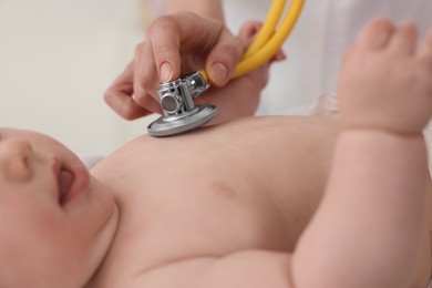 Photo of Pediatrician examining little baby with stethoscope in clinic, closeup