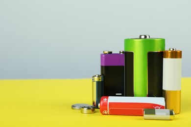 Different types of batteries on color background, space for text