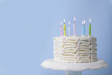 Photo of Delicious cake with cream and burning candles on light blue background. Space for text