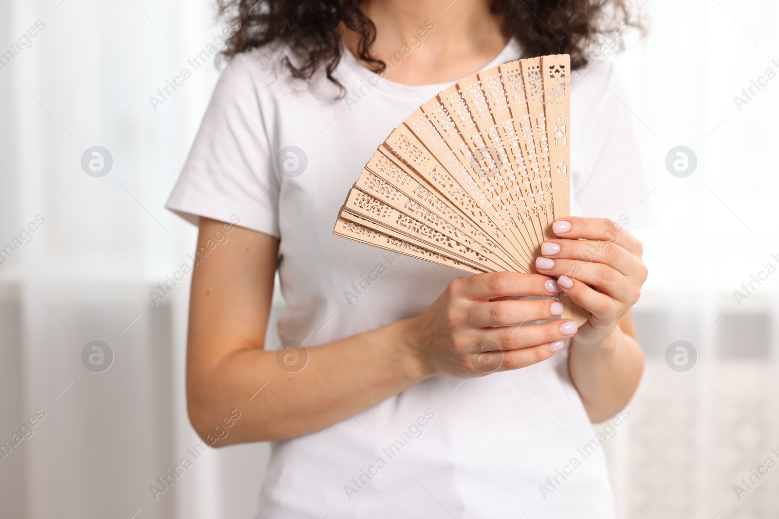 Photo of Woman with hand fan indoors, closeup view