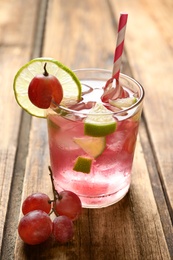 Photo of Soda water with grapes, ice and lime on wooden table. Refreshing drink