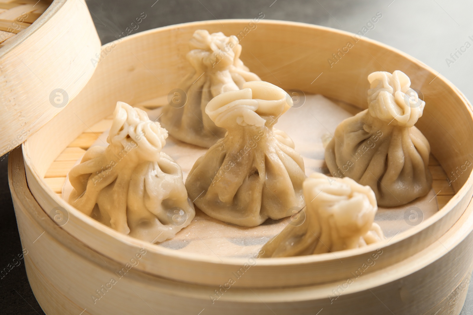 Photo of Bamboo steamer with tasty baozi dumplings, closeup