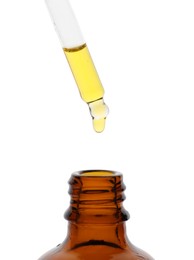 Photo of Dripping tincture from pipette into bottle isolated on white